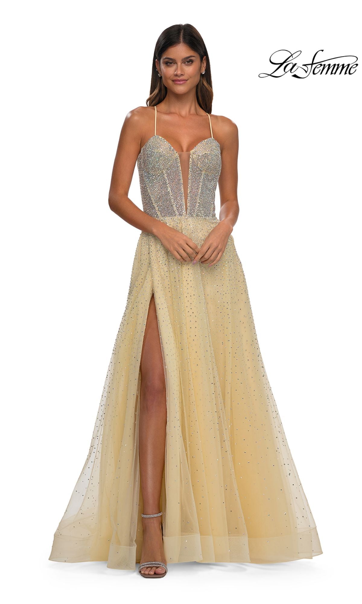 A woman in the Lace-Up Beaded Long Prom Ball Gown: La Femme 32725, a sleeveless, floor-length dress with a high slit and sparkling embellishments, stands facing forward. The La Femme logo appears in the top right corner.